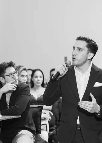 Alexis Abascal presenting with a microphone to the event audience.