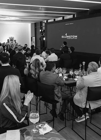 Event attendees seated at tables during the presentation.